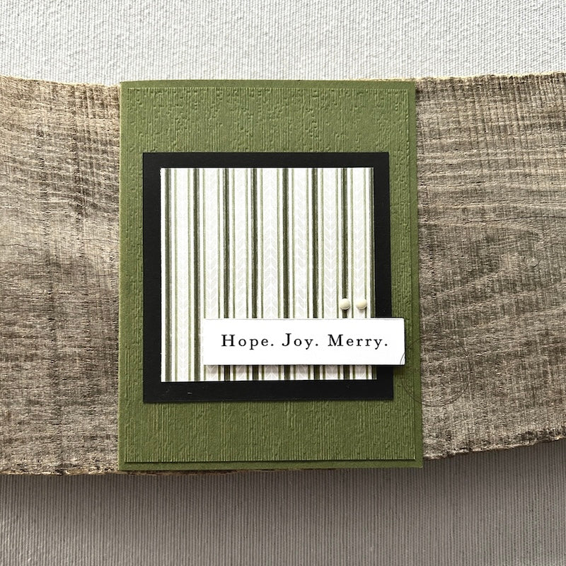 A finished card, from this card making kit, sitting on a wooden board.