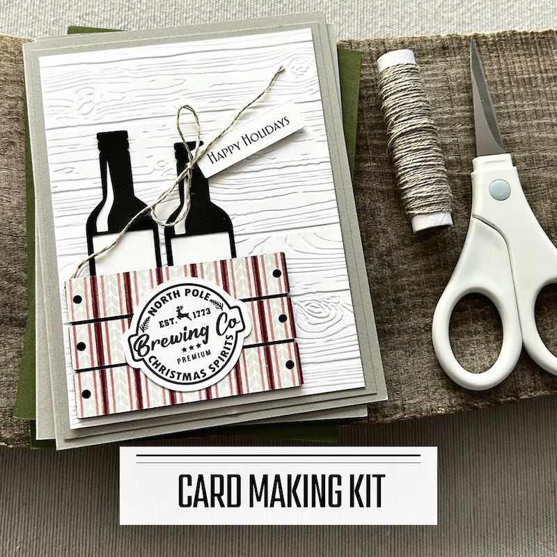 A DIY card making kit for 12 holiday cards. A finished card is sitting on blank cards with a roll of twine and scissors.