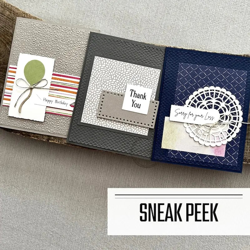 3 finished cards, from this card making kit, are sitting on a wooden board.