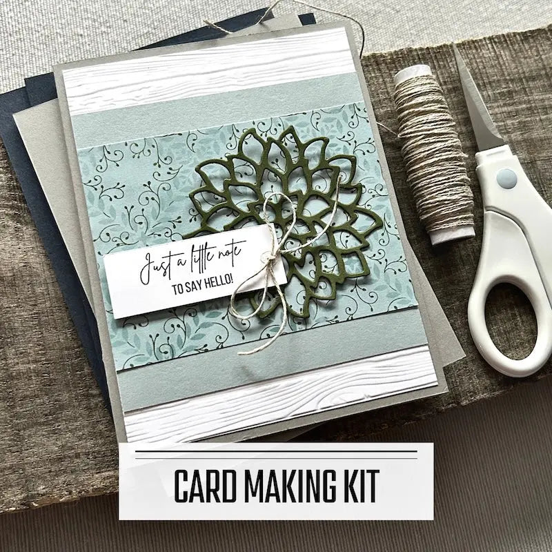 A DIY card making kit with assorted cards such as birthday, and thank-you et al. A finished card is sitting on blank cards with a roll of twine and a tape runner.