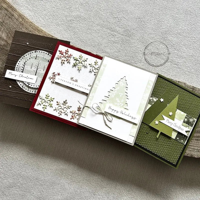 There are 4 finished cards, sitting on a wooden board, to show the finished cards that are included in this card making kit.