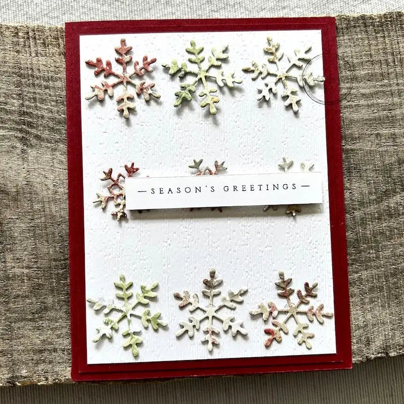 A finished card, from this card making kit, sitting on a wooden board.