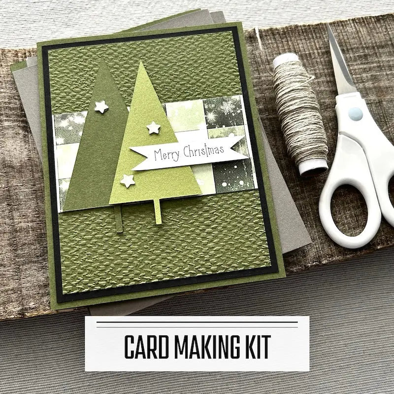 A DIY card making kit for Christmas. A finished card is sitting on blank cards with a roll of twine and a tape runner.