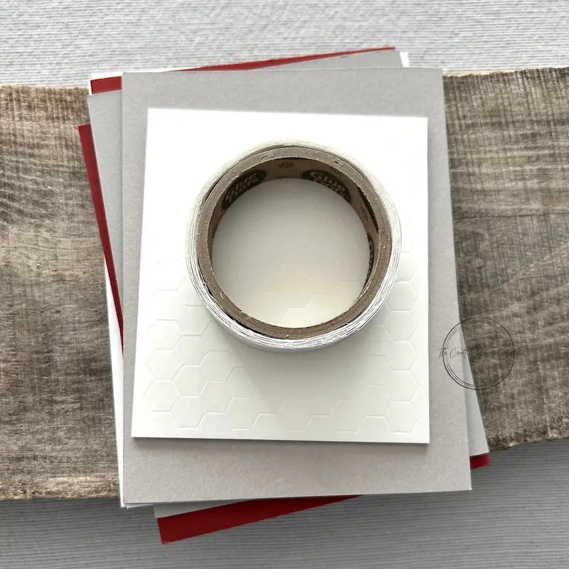A roll of glue dots and a sheet of pop dots are sitting on a few blank cards. They are included in your card making kit.
