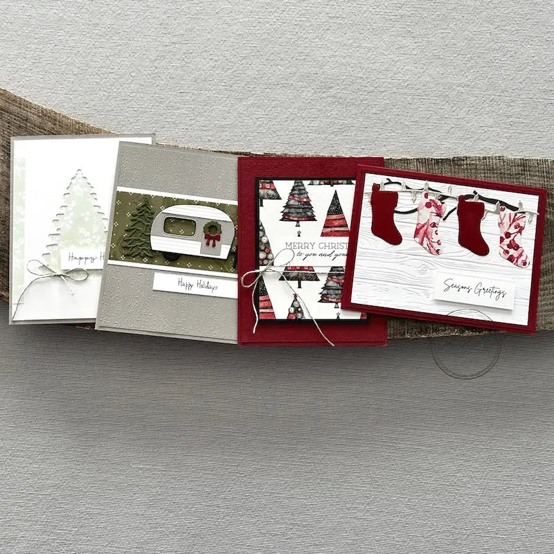 There are 4 finished cards, sitting on a wooden board, to show the finished cards that are included in this card making kit.
