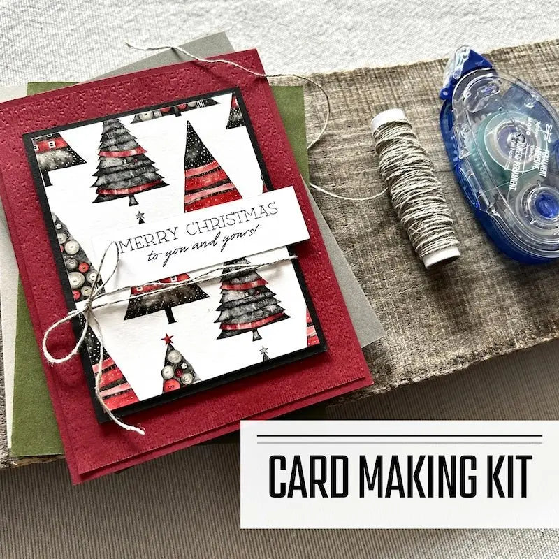 A DIY card making kit for Christmas. A finished card is sitting on blank cards with a roll of twine and a tape runner.