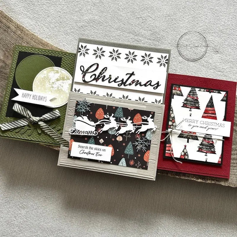 There are 4 finished cards, sitting on a wooden board, to show the finished cards that are included in this card making kit.