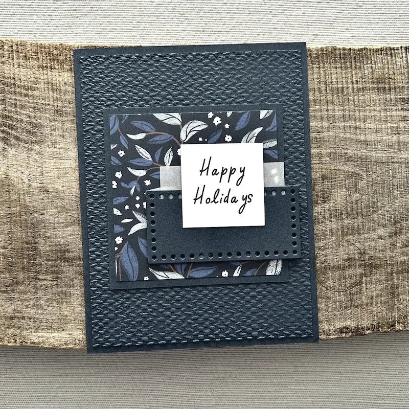 A finished card, from this card making kit, sitting on a wooden board.