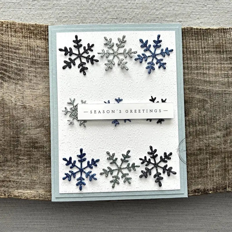 A finished card, from this card making kit, sitting on a wooden board.