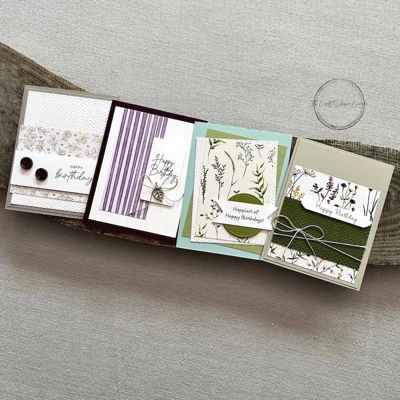 There are 4 finished cards, sitting on a wooden board, to show the finished cards that are included in this card making kit.
