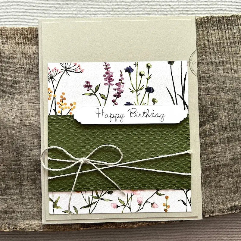 A finished card, from this card making kit, sitting on a wooden board.