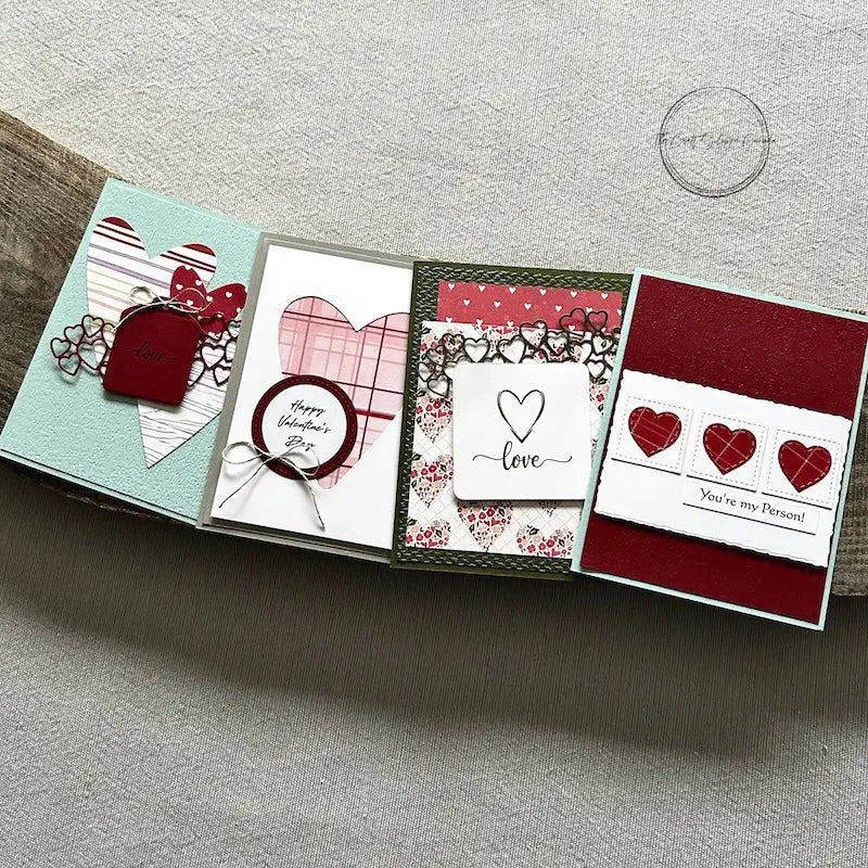 There are 4 finished cards, sitting on a wooden board, to show the finished cards that are included in this card making kit.