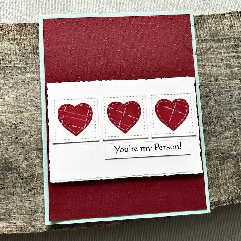A finished card, from this card making kit, sitting on a wooden board.