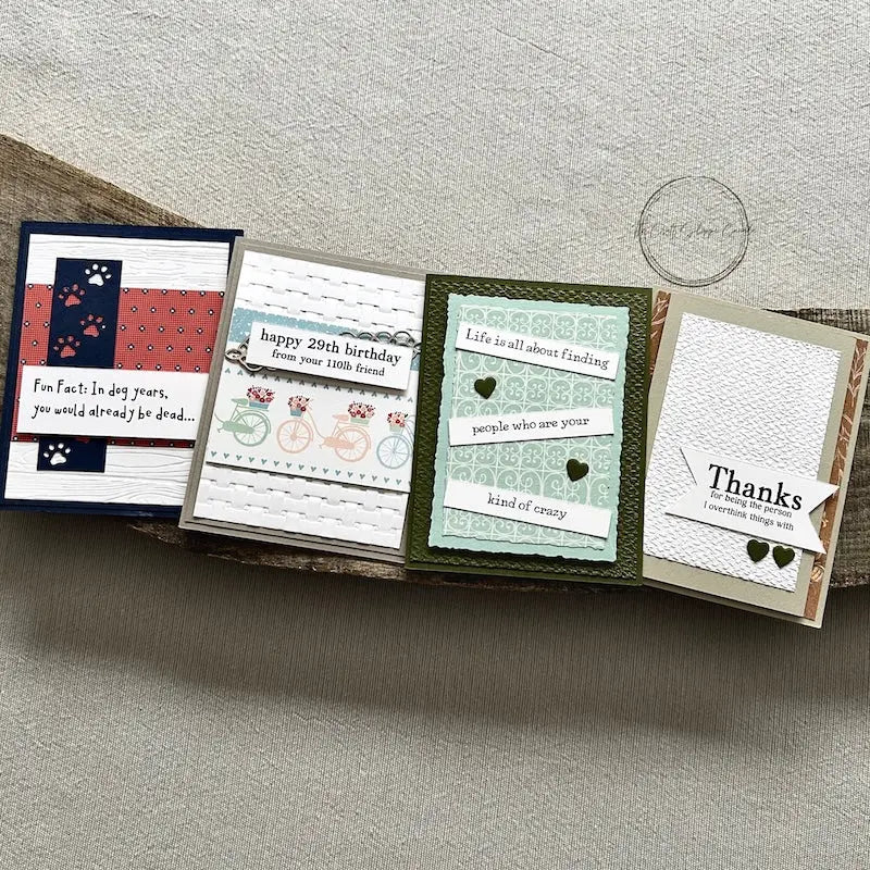 There are 4 finished cards, sitting on a wooden board, to show the finished cards that are included in this card making kit.