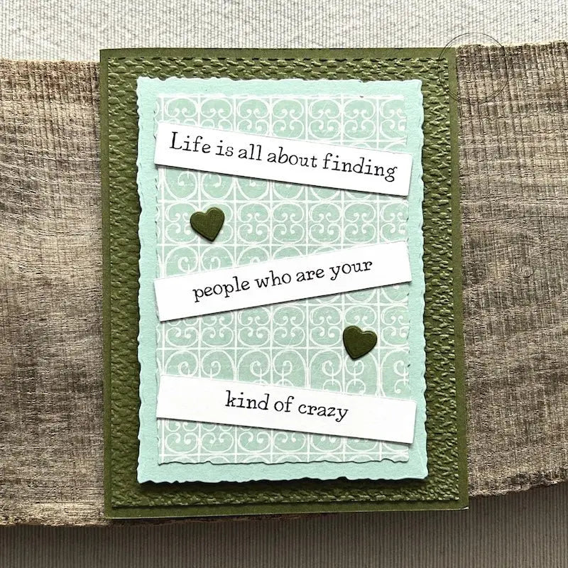 A finished card, from this card making kit, sitting on a wooden board.