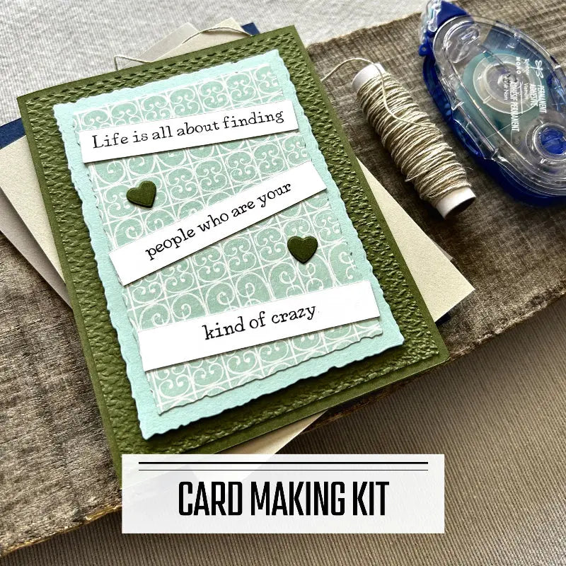 A DIY card making kit for cards with funny sentiments. A finished card is sitting on blank cards with a roll of twine and a tape runner.