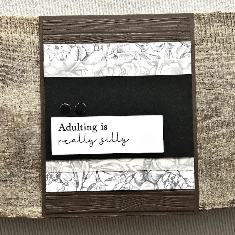 A finished card, from this card making kit, sitting on a wooden board.