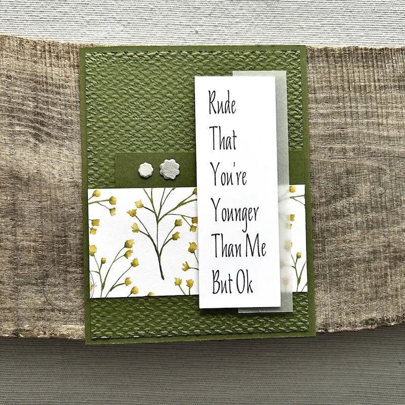 A finished card, from this card making kit, sitting on a wooden board.