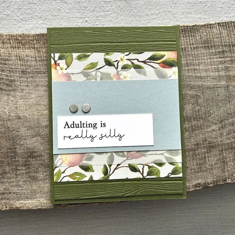 A finished card, from this card making kit, sitting on a wooden board.