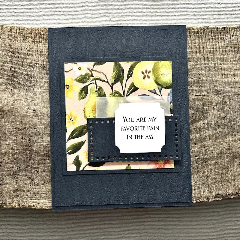 A finished card, from this card making kit, sitting on a wooden board.