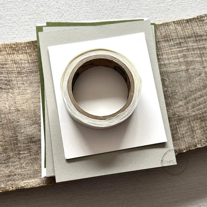 A roll of glue dots and a sheet of pop dots are sitting on a few blank cards. They are included in your card making kit.