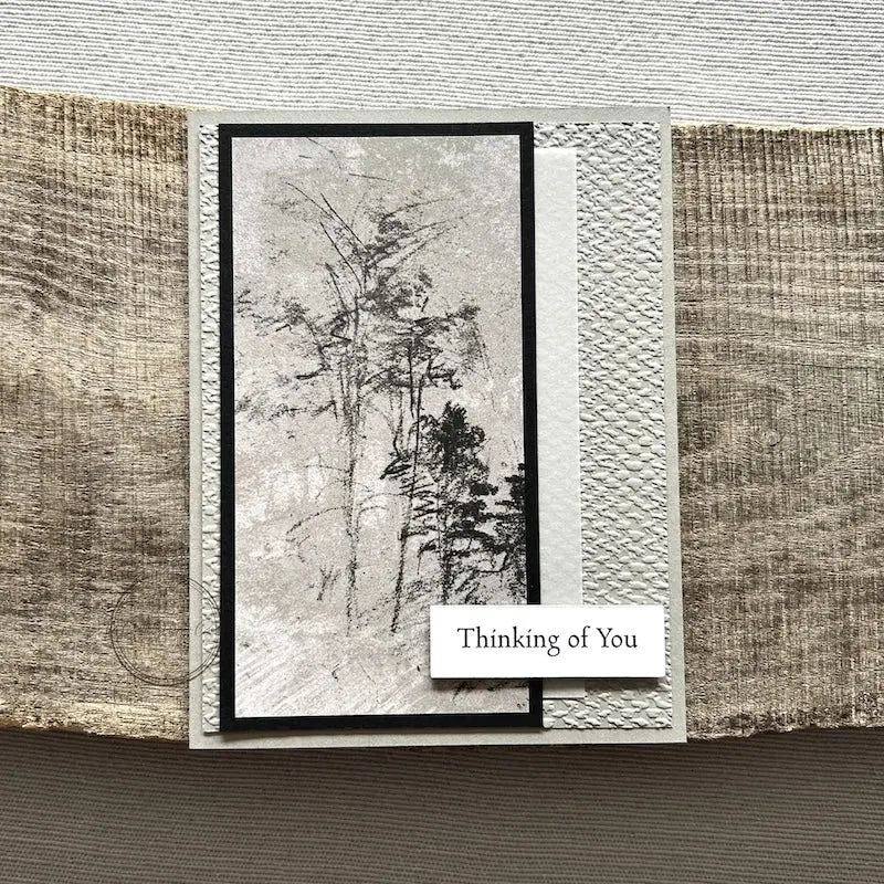 A finished card, from this card making kit, sitting on a wooden board.