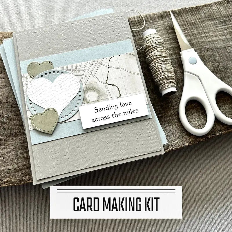 A DIY card making kit for Valentine's Day, wedding and anniversaries. A finished card is sitting on blank cards with a roll of twine and a pair of scissors.