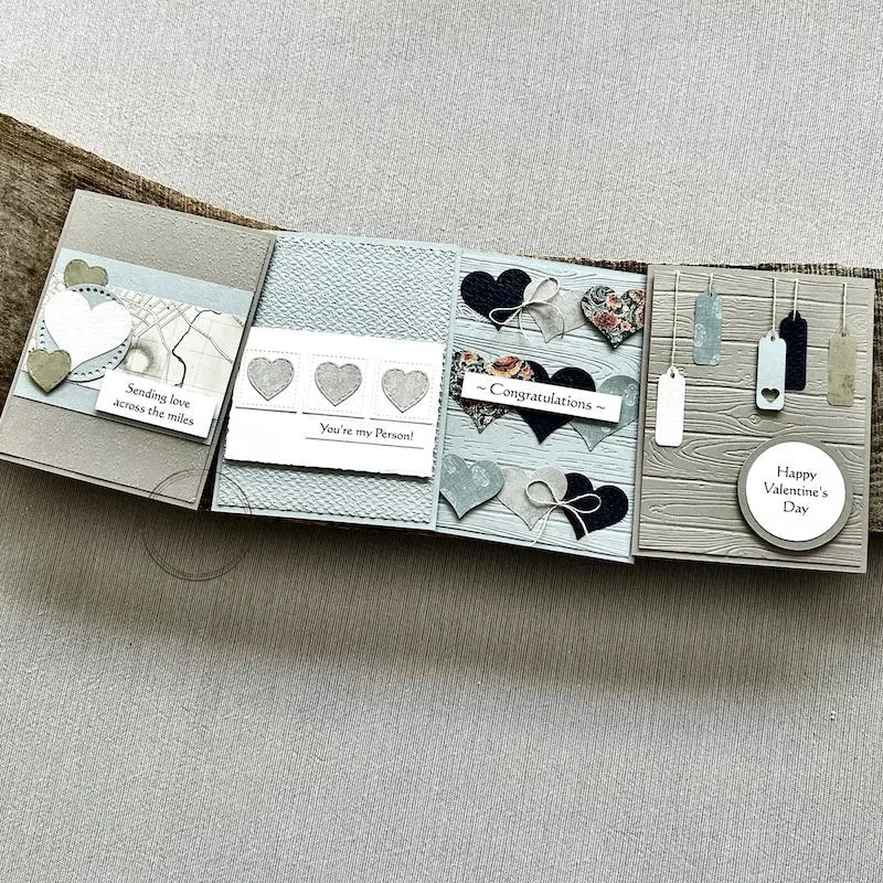 There are 4 finished cards, sitting on a wooden board, to show the finished cards that are included in this card making kit.