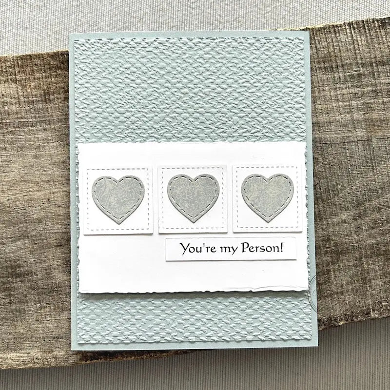 A finished card, from this card making kit, sitting on a wooden board.