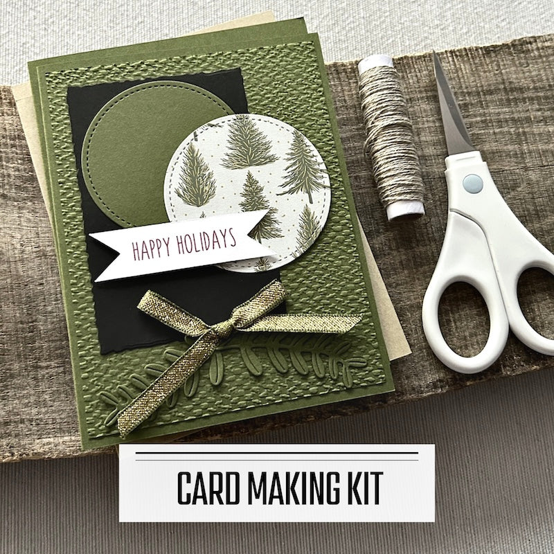 A DIY card making kit for Christmas. A finished card is sitting on blank cards with a roll of twine and a tape runner.