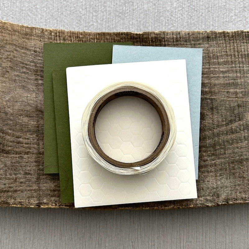 A roll of glue dots and a sheet of pop dots are sitting on a few blank cards. They are included in your gift tag kit.