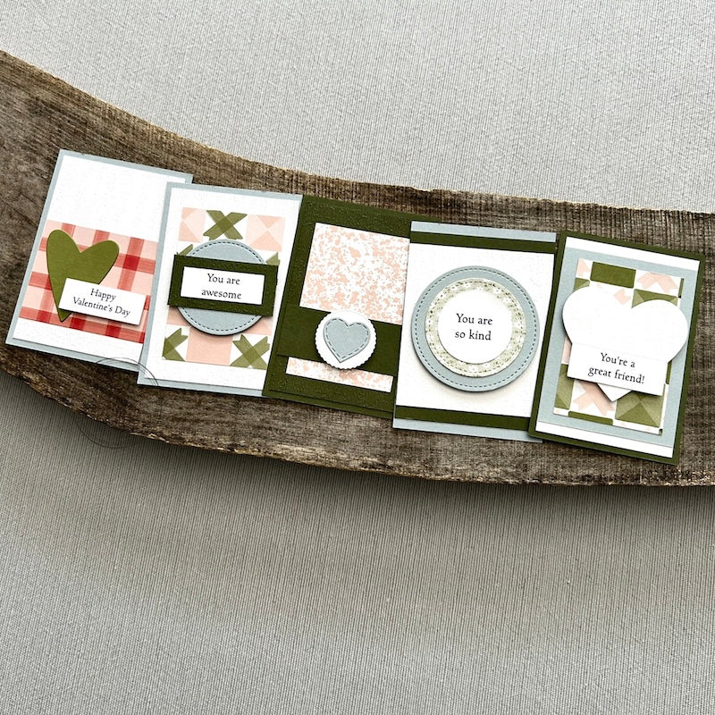 There are 5 finished valentines, sitting on a wooden board, to show the finished cards that are included in this kit.