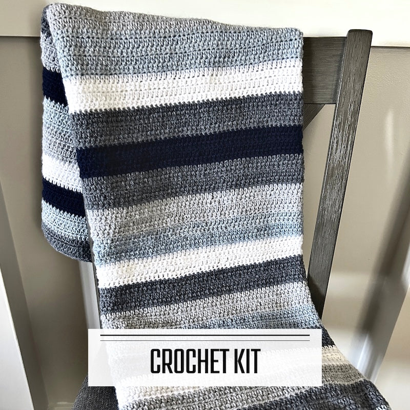 A crochet kit for a couch throw blanket. The finished blanket is lying over a chair.