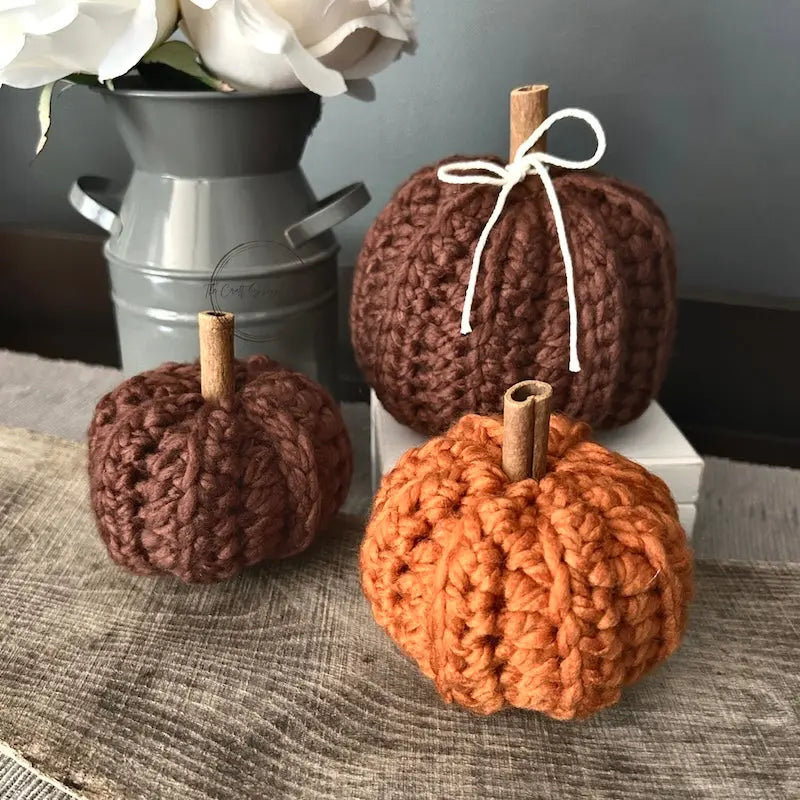 A set of finished pumpkins, made from this crochet kit are sitting on a wooden board.