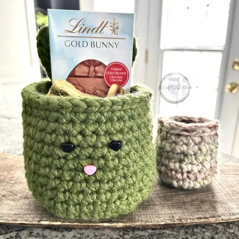 The Easter basket set is sitting on a wooden board with chocolates inside and out of the baskets.