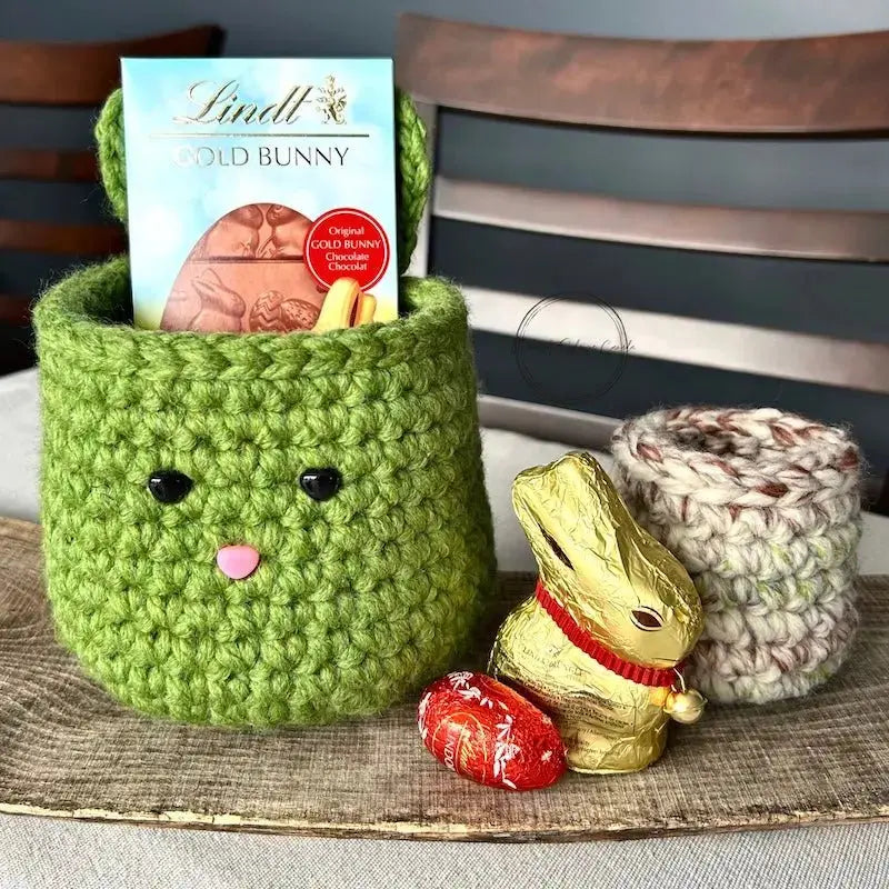 The Easter baskets from this crochet kit are sitting on a wooden board with chocolates inside and out of the baskets.