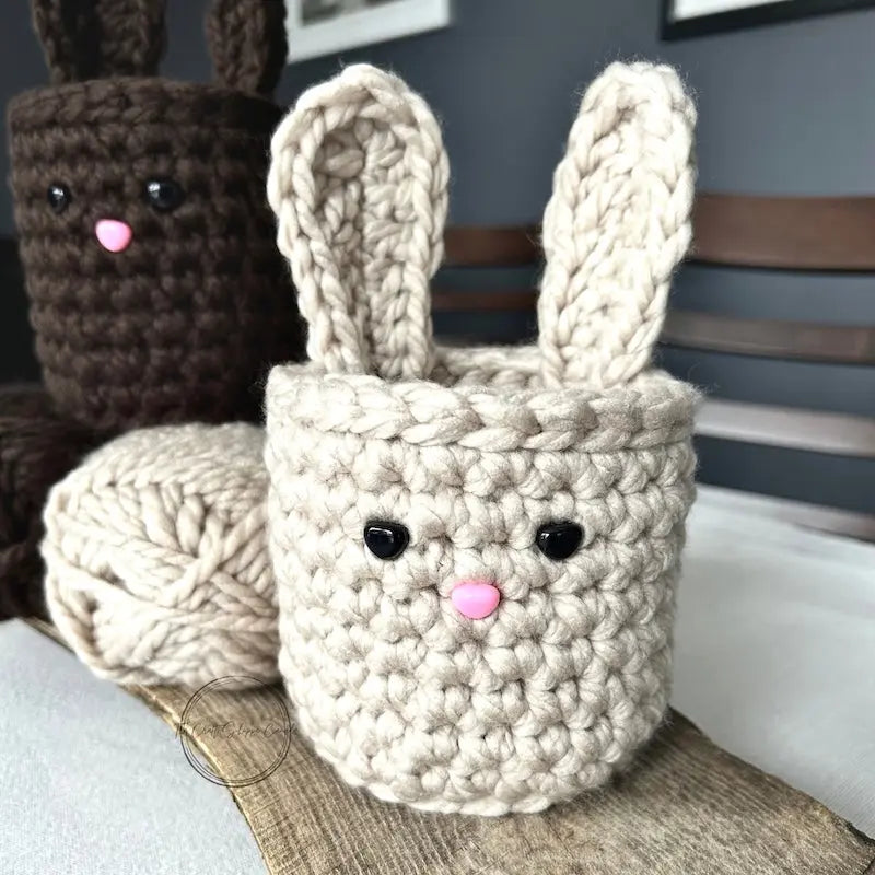 The finished easter bunny baskets are sitting on a wooden board with a ball of yarn.