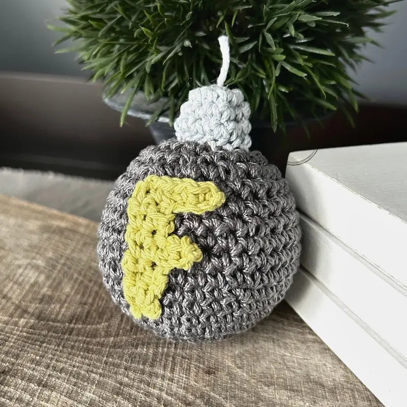 The F bomb, made from this crochet kit, is sitting on a wooden board.