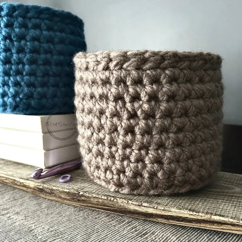 The storage basket, from this crochet kit, is sitting on a wooden board.