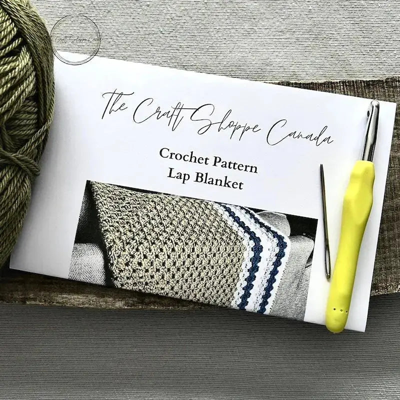 The pattern for this crochet kit is lying on a wooden board with yarn, a crochet hook, and a tapestry needle.