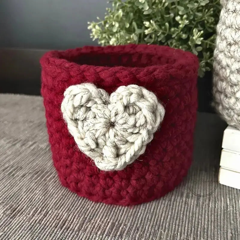A closer look at the heart basket, made from this crochet pattern, sitting on a table.
