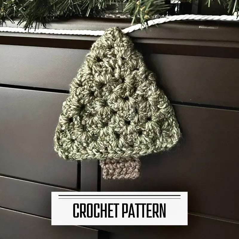 A DIY crochet pattern for a Christmas tree garland. The garland is hanging on off of a buffet with a pine garland on top.