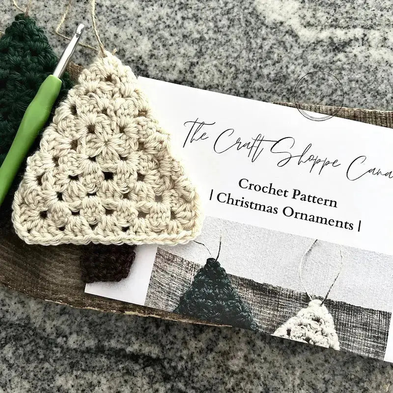 The pattern, is lying on a wooden board with the finished ornaments and a crochet hook.