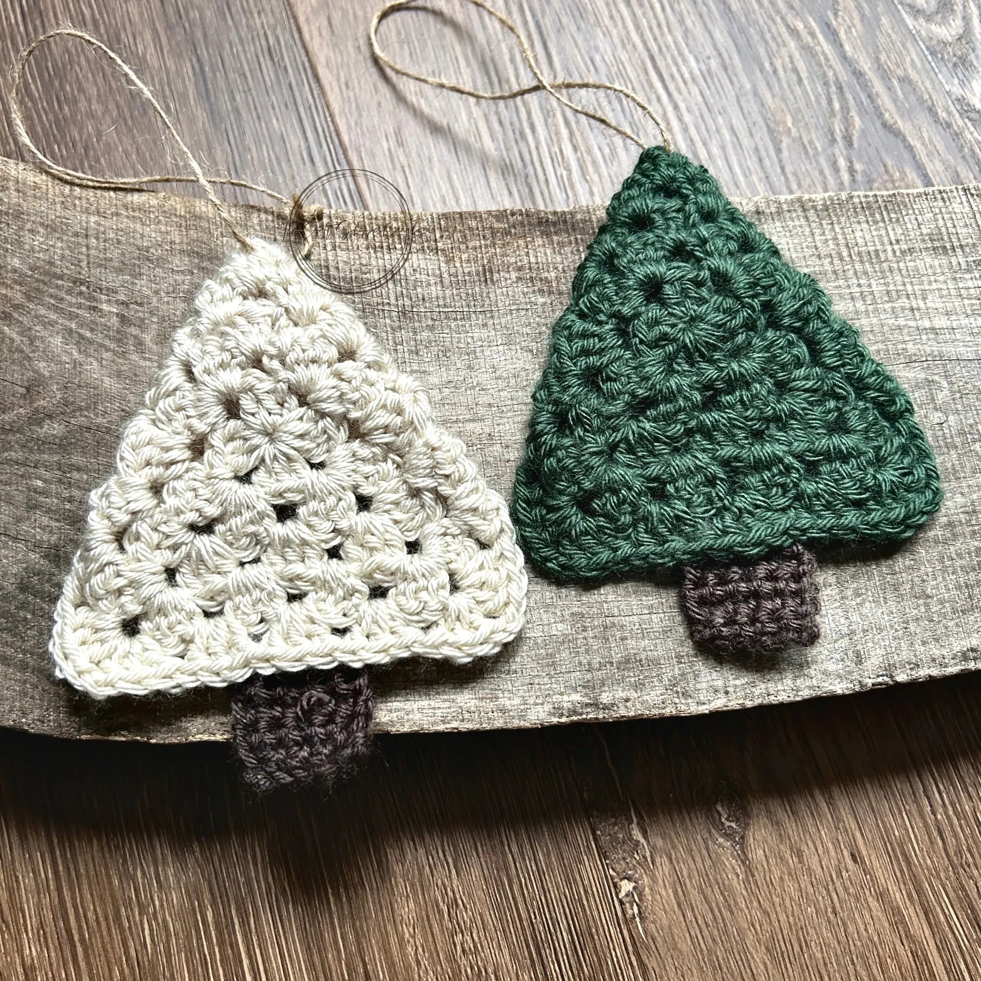 A green and ivory Christmas tree ornament, made from this crochet pattern, are sitting on a wooden board.