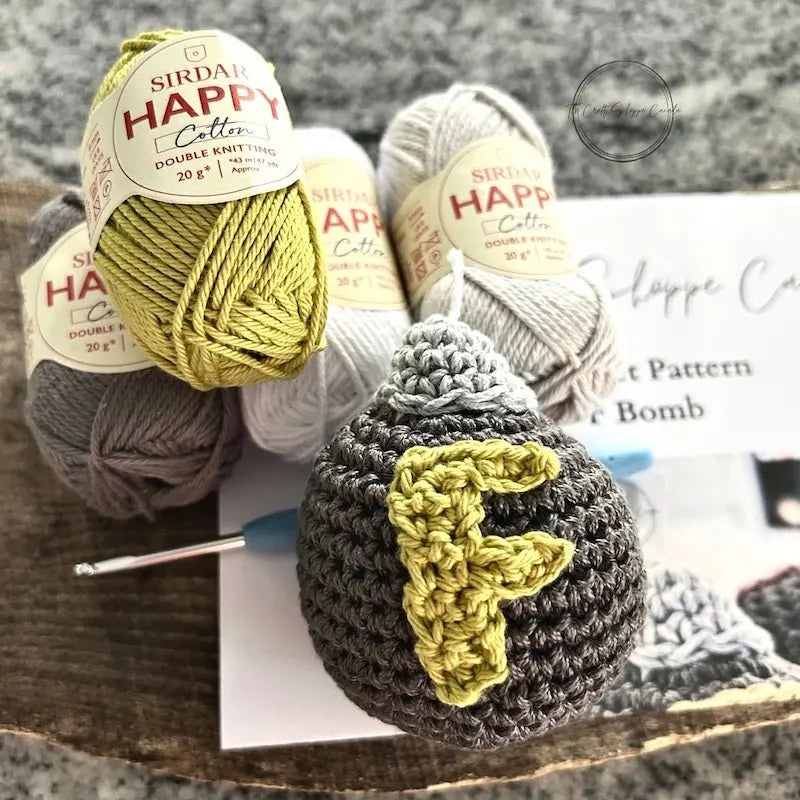 Close-up of the F-Bomb plush, made from this crochet pattern, with yarn, and a crochet hook.