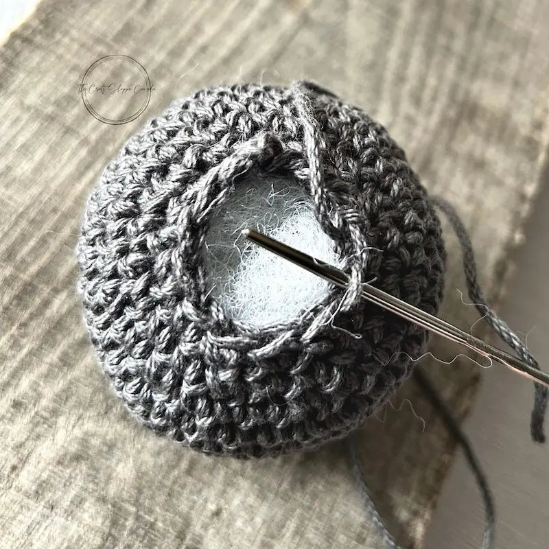 A close up of the top of the F Bomb, made from this crochet pattern, to show the stuffing inside with a tapestry needle closing up the top.
