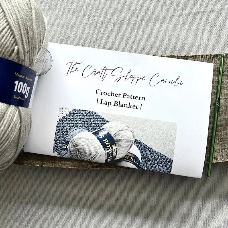 The crochet pattern is lying on a wooden board with yarn, and a crochet hook.