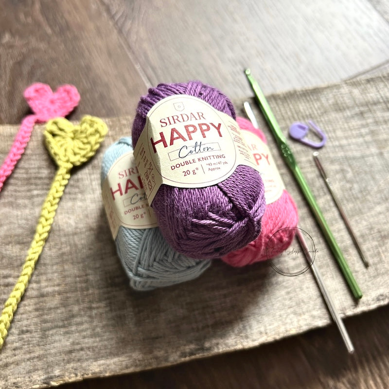 The finished bookmarks, made from this crochet kit, are lying on a board with yarn and crochet hooks.