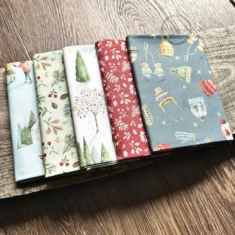 A stack of fabric, that would be used to make this cross stitch pattern, is sitting on a wooden table.