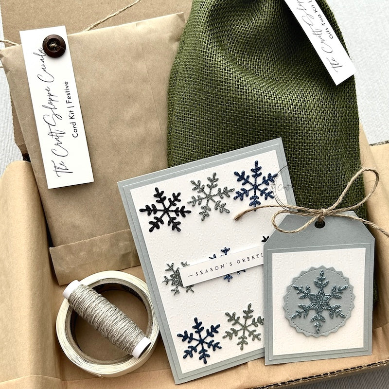A look at the card making and gift tag kits if the bundle is ordered. A finished card and gift tag are sitting in a box with the full two kits.